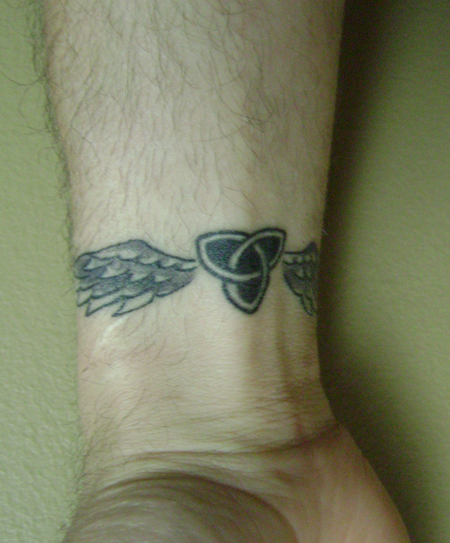 grey-ink-winged-celtic-knot-tattoo-on-wrist